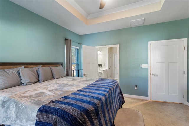 carpeted bedroom featuring ensuite bathroom, ceiling fan, and a tray ceiling