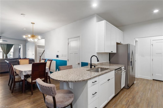 kitchen featuring light stone countertops, sink, stainless steel appliances, light hardwood / wood-style flooring, and white cabinets