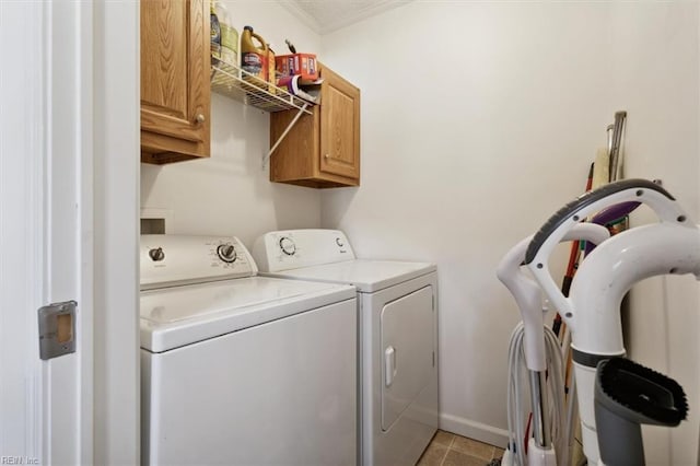 laundry area with crown molding, washer and clothes dryer, light tile patterned flooring, and cabinets