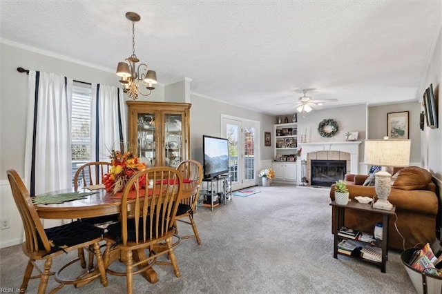 carpeted dining room featuring a fireplace, a textured ceiling, ceiling fan with notable chandelier, and crown molding