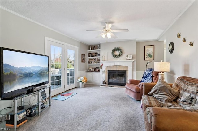 living room featuring carpet flooring, ceiling fan, crown molding, and a tiled fireplace