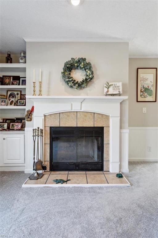 room details featuring crown molding, built in shelves, a textured ceiling, carpet floors, and a tiled fireplace