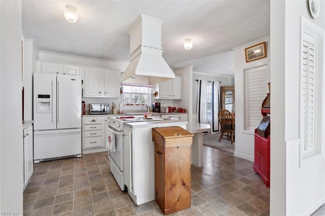 kitchen featuring white cabinetry, a center island, a textured ceiling, white appliances, and custom range hood