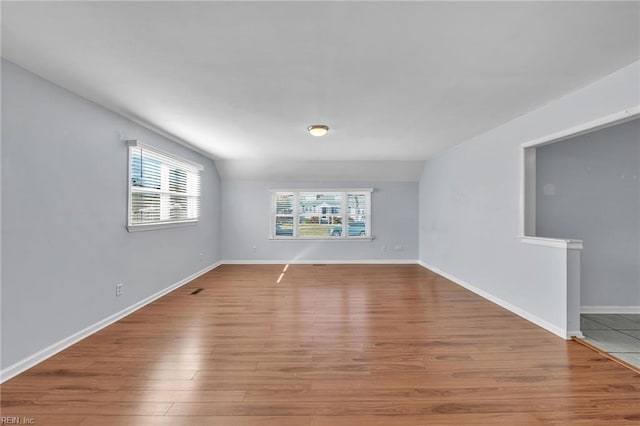 unfurnished room with light hardwood / wood-style flooring and vaulted ceiling