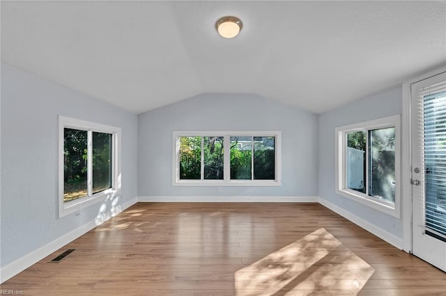 spare room featuring lofted ceiling and light wood-type flooring