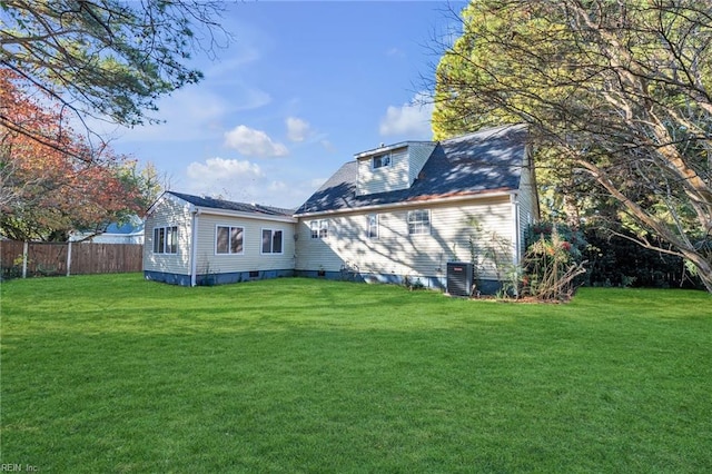 rear view of property featuring central air condition unit and a yard