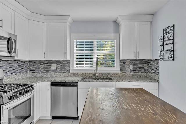 kitchen featuring white cabinets, stainless steel appliances, light stone counters, and sink