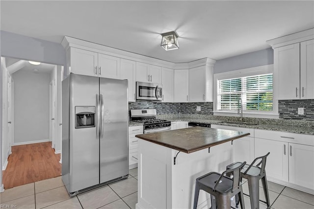 kitchen with a kitchen breakfast bar, sink, white cabinets, and appliances with stainless steel finishes