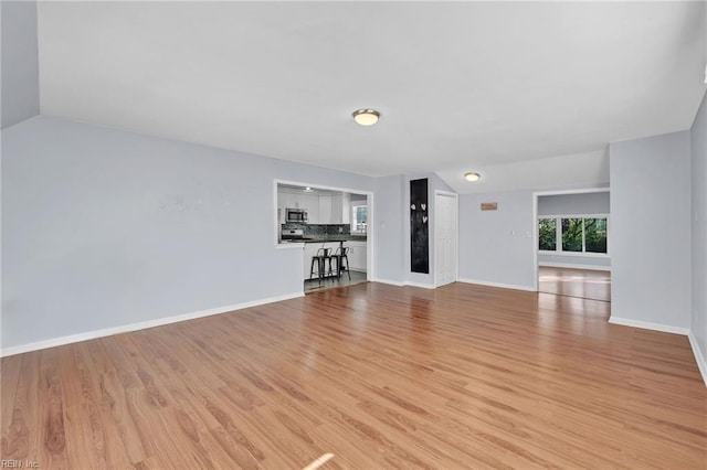 unfurnished living room featuring lofted ceiling and light wood-type flooring