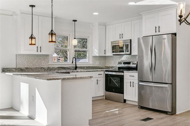 kitchen featuring kitchen peninsula, white cabinets, and appliances with stainless steel finishes