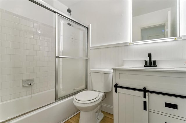 full bathroom featuring vanity, toilet, combined bath / shower with glass door, and wood-type flooring