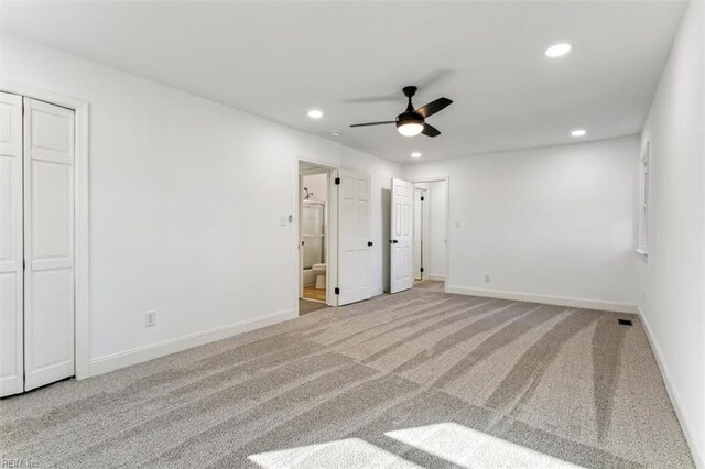 unfurnished bedroom featuring light carpet, ensuite bath, and ceiling fan