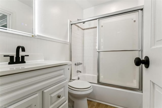 full bathroom featuring vanity, toilet, combined bath / shower with glass door, and wood-type flooring