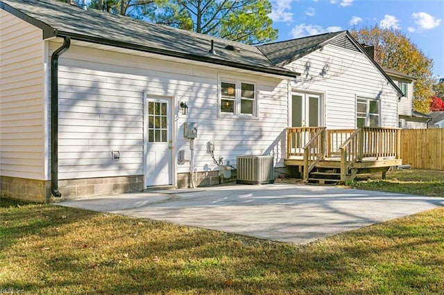 rear view of house with a patio, cooling unit, and a lawn