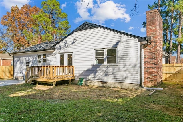 rear view of house with french doors, a deck, and a lawn