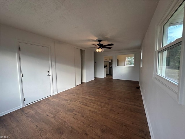 unfurnished room with ceiling fan, dark hardwood / wood-style flooring, a textured ceiling, and a wealth of natural light