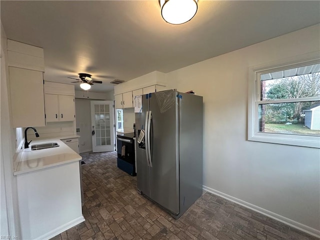 kitchen with black electric range oven, sink, stainless steel fridge with ice dispenser, ceiling fan, and white cabinetry