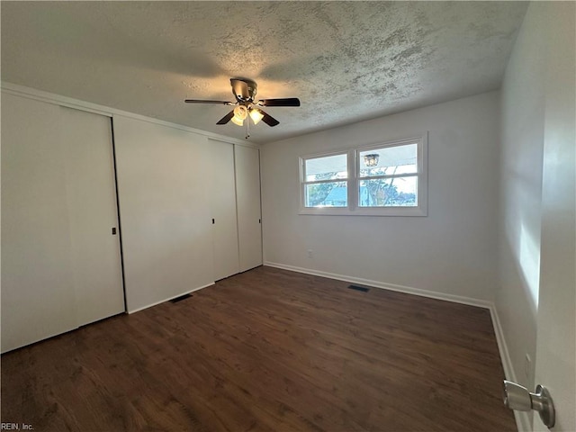 unfurnished bedroom featuring a textured ceiling, ceiling fan, and dark wood-type flooring