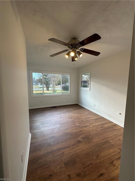 spare room featuring dark hardwood / wood-style floors, lofted ceiling, and a textured ceiling