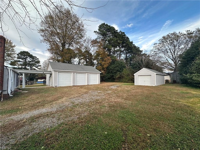 view of yard featuring a carport, an outdoor structure, and a garage