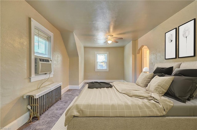 bedroom with carpet, ceiling fan, radiator, and multiple windows