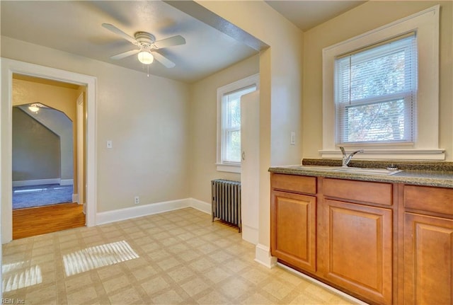 kitchen with a wealth of natural light, ceiling fan, sink, and radiator