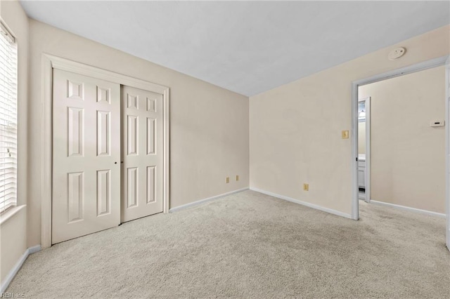 unfurnished bedroom with multiple windows, a closet, and light colored carpet