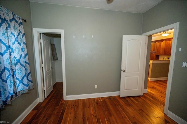 unfurnished bedroom featuring dark hardwood / wood-style floors and ensuite bathroom