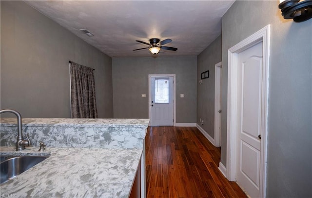 interior space with light stone counters, ceiling fan, dark wood-type flooring, and sink