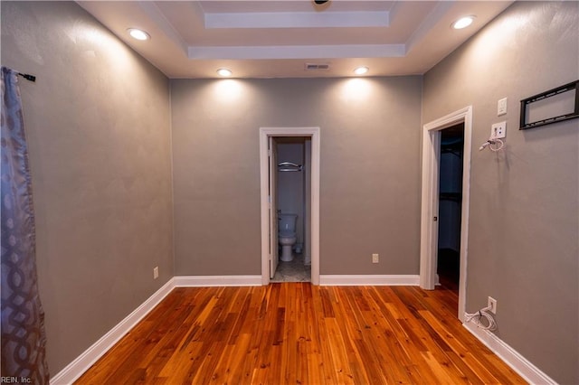 empty room featuring hardwood / wood-style floors and a tray ceiling