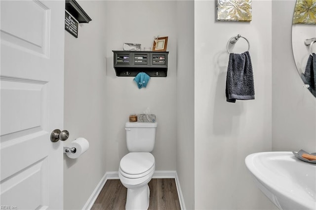 bathroom with toilet, wood-type flooring, and sink