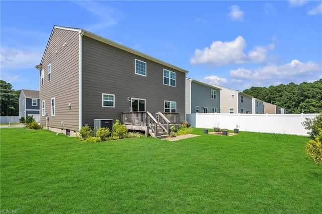 rear view of property with a yard, a wooden deck, and central AC