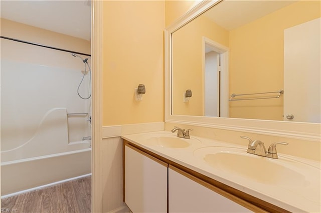 bathroom with hardwood / wood-style flooring, vanity, and shower / bathtub combination