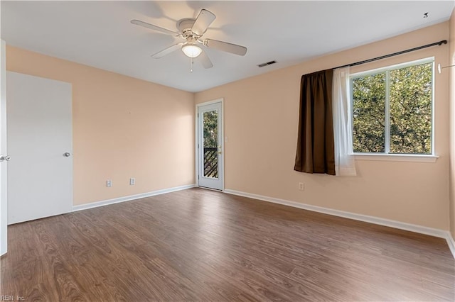 spare room featuring visible vents, wood finished floors, baseboards, and ceiling fan