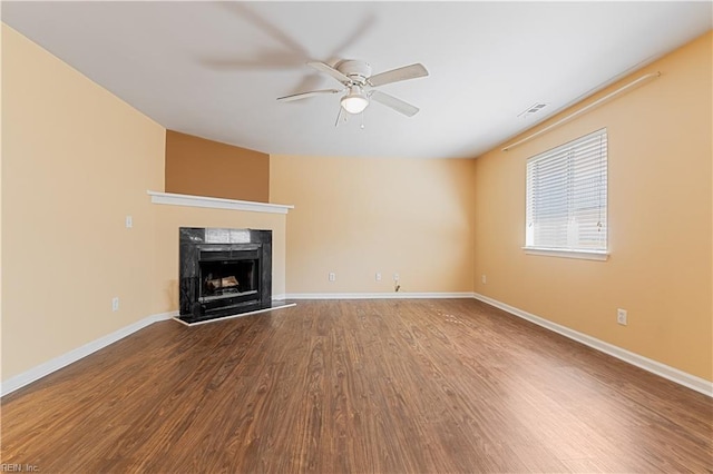 unfurnished living room with a high end fireplace, visible vents, ceiling fan, baseboards, and wood finished floors