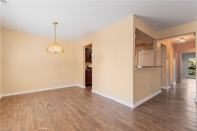 unfurnished room featuring dark wood-type flooring and a notable chandelier