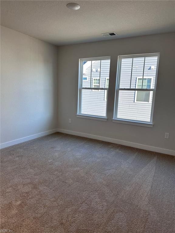 carpeted empty room with a textured ceiling