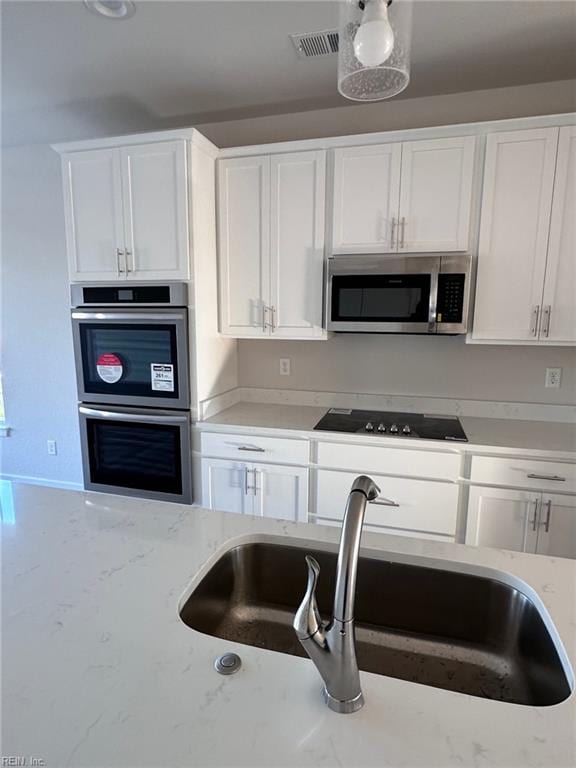 kitchen featuring light stone counters, sink, stainless steel appliances, and white cabinets