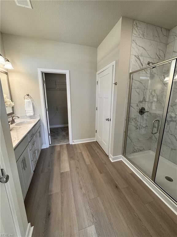 bathroom with vanity, hardwood / wood-style floors, a shower with shower door, and a textured ceiling