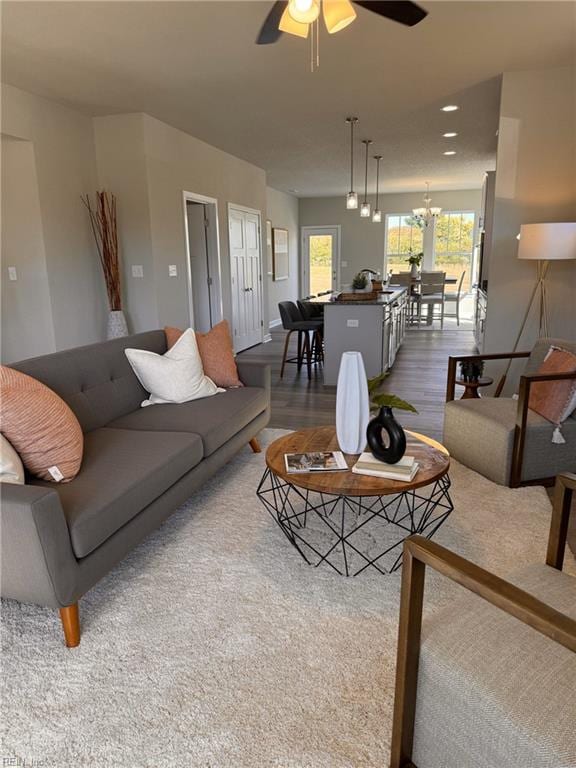 living room featuring ceiling fan with notable chandelier and hardwood / wood-style floors