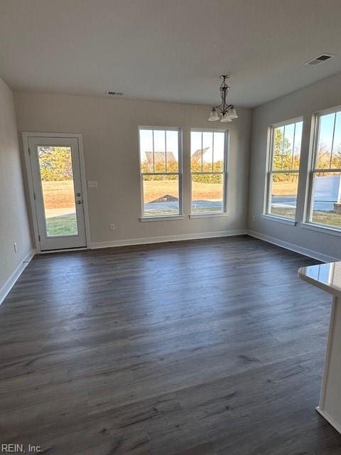 unfurnished dining area featuring dark wood-type flooring and a chandelier