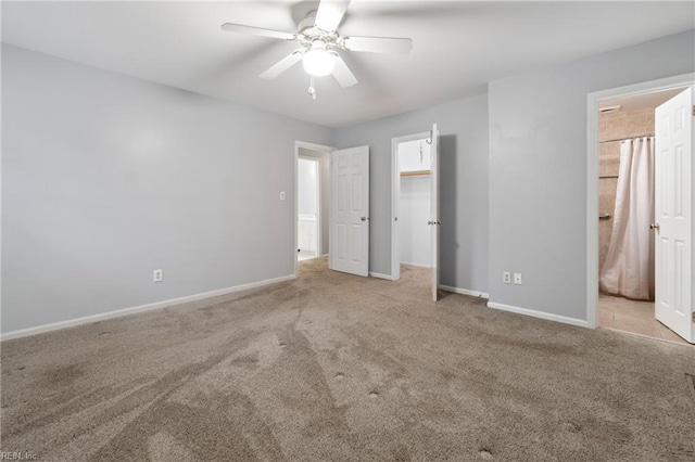 unfurnished bedroom featuring a walk in closet, ensuite bathroom, ceiling fan, and light colored carpet