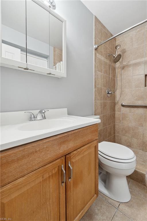 bathroom featuring tile patterned flooring, vanity, toilet, and a tile shower