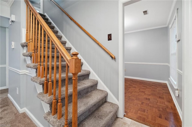 stairway with crown molding and parquet floors