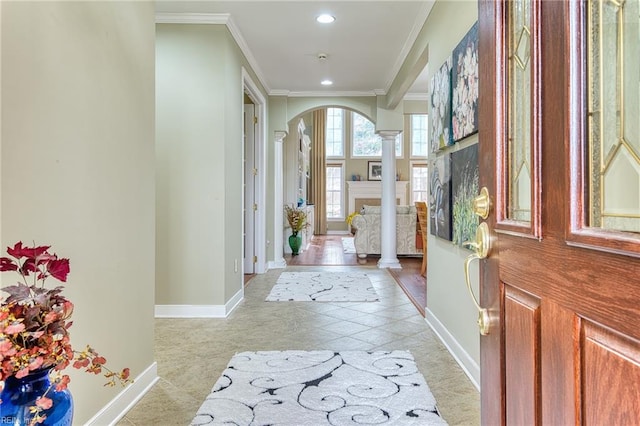 foyer featuring light tile patterned floors, decorative columns, and crown molding