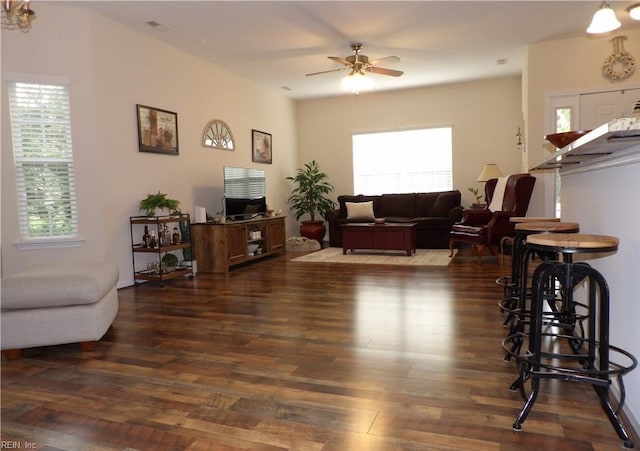 living room featuring dark wood-type flooring, ceiling fan, and a healthy amount of sunlight