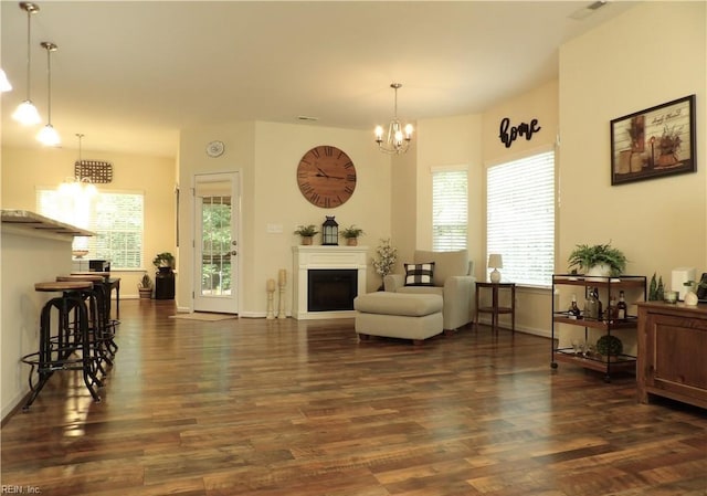 living room featuring dark hardwood / wood-style flooring, a wealth of natural light, and a notable chandelier