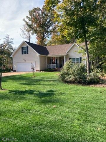 ranch-style house with covered porch, a garage, and a front lawn