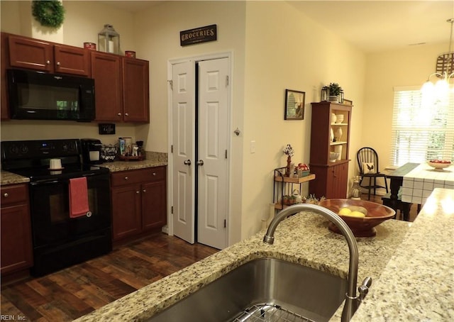 kitchen with black appliances, dark hardwood / wood-style floors, light stone countertops, and decorative light fixtures