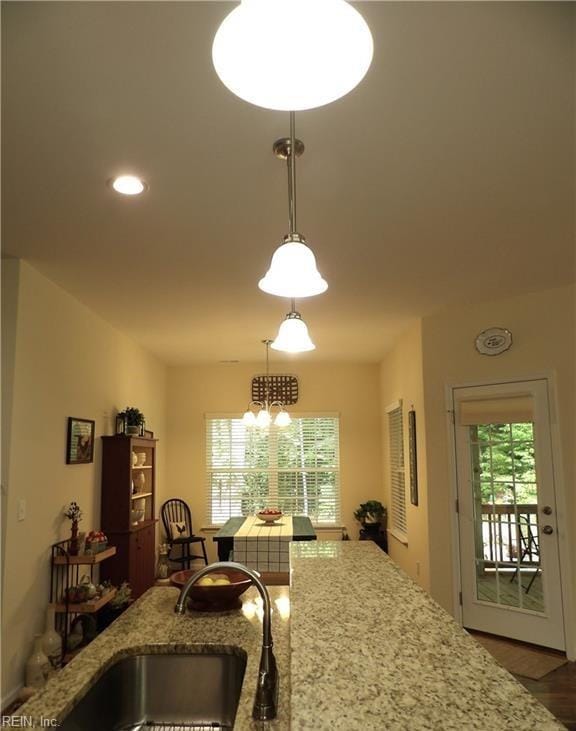 kitchen featuring light stone countertops, sink, a healthy amount of sunlight, and decorative light fixtures